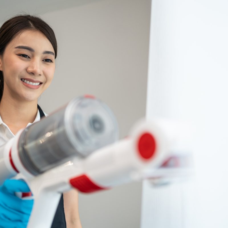 Asian cleaning service woman worker cleaning in living room at home.